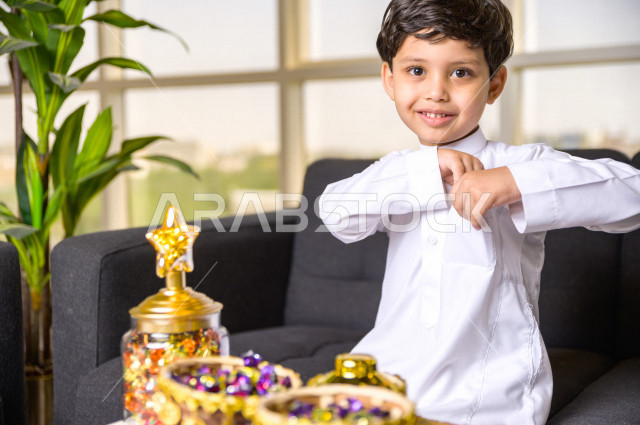 طفل سعودي خليجي في صباح يوم العيد إيماءات و تعابير وجه تدل على السعادة بأخذ عيدية العيد  ، يرتدي اللباس السعودي التقليدي ، العيدية ، القرقيعان ، احتفالات و مظاهر العيد ، قضاء أوقات عائلية سعيدة في العيد