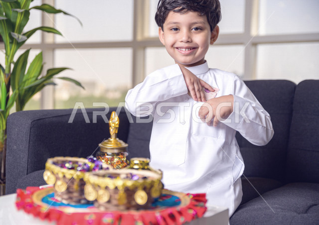 طفل سعودي خليجي في صباح يوم العيد إيماءات و تعابير وجه تدل على السعادة بأخذ عيدية العيد  ، يرتدي اللباس السعودي التقليدي ، العيدية ، القرقيعان ، احتفالات و مظاهر العيد ، قضاء أوقات عائلية سعيدة في العيد