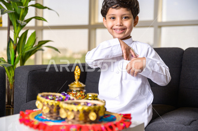 طفل سعودي خليجي في صباح يوم العيد إيماءات و تعابير وجه تدل على السعادة بأخذ عيدية العيد  ، يرتدي اللباس السعودي التقليدي ، العيدية ، القرقيعان ، احتفالات و مظاهر العيد ، قضاء أوقات عائلية سعيدة في العيد