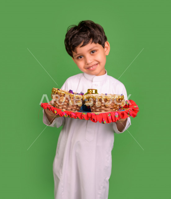 كروما لطفل سعودي عربي خليجي في صباح يوم العيد بإيماءات تدل على السعادة ، يرتدي اللباس السعودي التقليدي ، العيدية ، القرقيعان ، خلفية خضراء