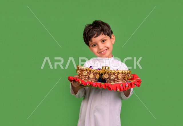 كروما لطفل سعودي عربي خليجي في صباح يوم العيد بإيماءات تدل على السعادة ، يرتدي اللباس السعودي التقليدي ، العيدية ، القرقيعان ، خلفية خضراء
