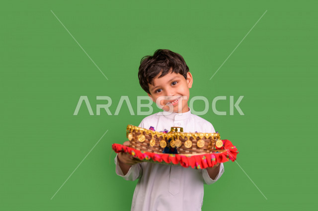 كروما لطفل سعودي عربي خليجي في صباح يوم العيد بإيماءات تدل على السعادة ، يرتدي اللباس السعودي التقليدي ، العيدية ، القرقيعان ، خلفية خضراء