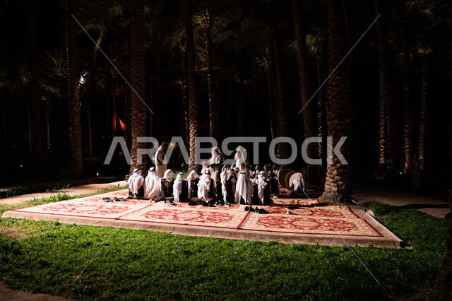 مجموعة من الرجال العرب الخليجيين السعودين يجلسون وسط النخيل ليلا، حفلة سامري، سامري وسط النخيل، حفلة موسيقية، اشجار النخيل، العرضة السعودية
