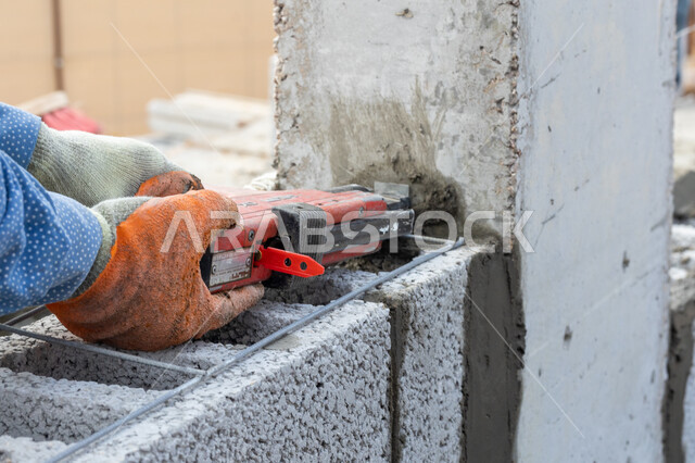 صورة مقربة لعامل بناء يقوم ببناء جدار من الطوب والاسمنت، قالب طوبي، اعمال البناء، حائط حجري، ادوات ومعدات البناء