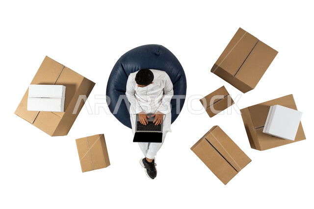 الشراء عن طريق الانترنت, استخدام الحاسوب المحمول في عملية التسوق الالكتروني ، عملية شحن وتوصيل موثوقه, بورتريه علوي عامودي لرجل عربي سعودي يرتدي الزي السعودي يجلس على كرسي مريح ,خلفيه بيضاء