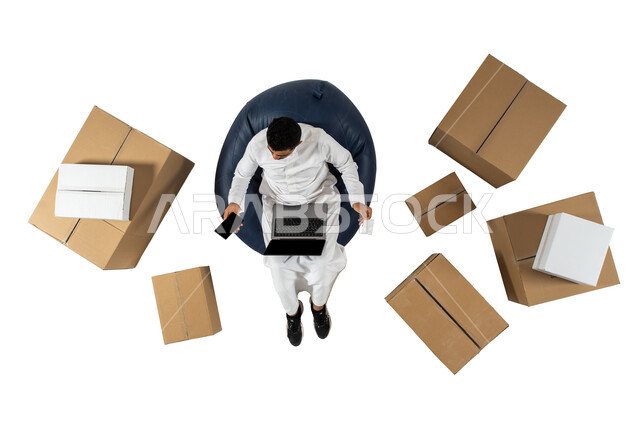 عملية شحن وتوصيل موثوقه, الدفع عن طريق البطاقه البنكيه في طلبات الاونلاين, بورتريه علوي عامودي لرجل عربي سعودي يرتدي الزي السعودي يجلس على كرسي مريح ، التسوق عبر جهاز الحاسوب المحمول, الشراء عن طريق الانترنت, خلفيه بيضاء