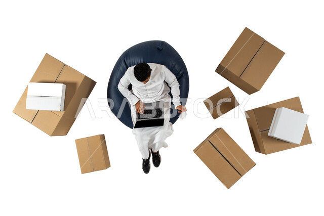 Payment by bank card in online requests, vertical portrait of a Saudi Arabian man wearing Saudi dress sitting on a comfortable chair, shopping via a laptop, reliable shipping and delivery, online purchase, white background