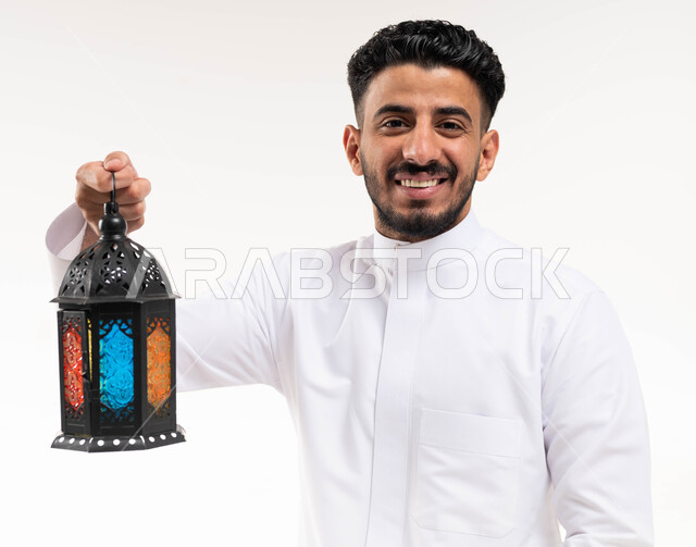 Portrait of a Saudi Arabian Gulf man, carrying a Ramadan lantern, preparing for the advent of the blessed month of Ramadan, religious occasions and Islamic holidays, Ramadan Kareem, Islamic and worship, white background