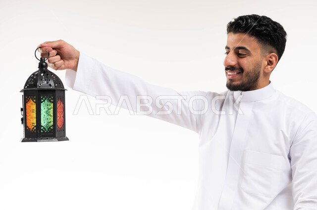 Portrait of a Saudi Arabian Gulf man, carrying a Ramadan lantern, preparing for the advent of the blessed month of Ramadan, religious occasions and Islamic holidays, Ramadan Kareem, Islamic and worship, white background