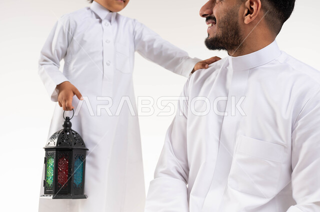 صورة مقربة لرجل عربي خليجي سعودي مع إبنه ، فانوس رمضان ، الإستعداد لقدوم شهر رمضان المبارك ، المناسبات الدينية والأعياد الإسلامية ، رمضان كريم ، إسلاميات وعبادة ، خلفية بيضاء