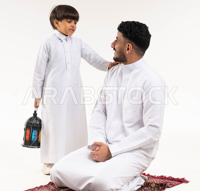 بورتريه لرجل عربي خليجي سعودي مع إبنه ، فانوس رمضان ، الإستعداد لقدوم شهر رمضان المبارك ، المناسبات الدينية والأعياد الإسلامية ، رمضان كريم ، إسلاميات وعبادة ، خلفية بيضاء ، صورة بالطول الكامل
