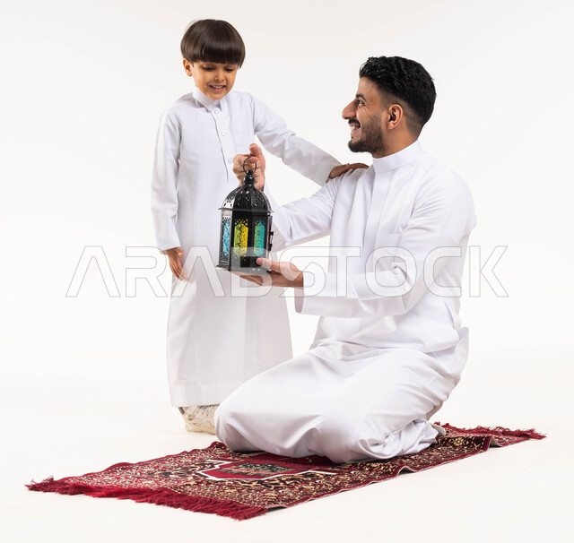 Portrait of a Saudi Arab Gulf man with his son, Ramadan lantern, preparing for the advent of the blessed month of Ramadan, religious occasions and Islamic holidays, Ramadan Kareem, Islamic and worship, white background, full length photo