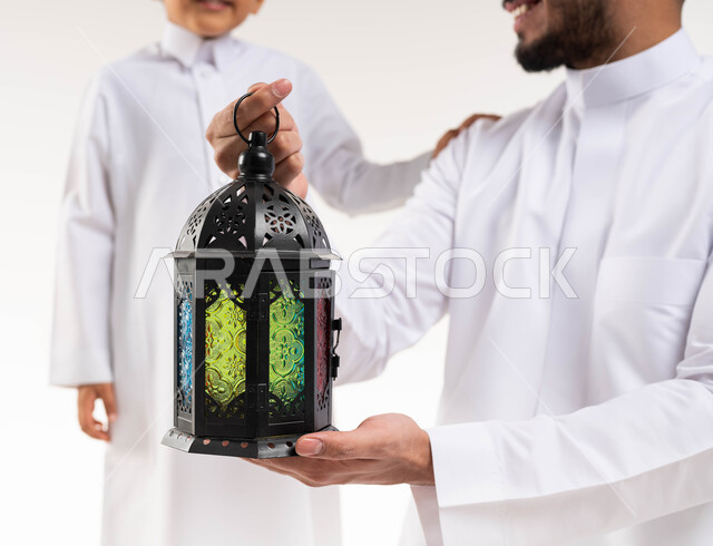 صورة مقربة لرجل عربي خليجي سعودي مع إبنه ، فانوس رمضان ، الإستعداد لقدوم شهر رمضان المبارك ، المناسبات الدينية والأعياد الإسلامية ، رمضان كريم ، إسلاميات وعبادة ، خلفية بيضاء