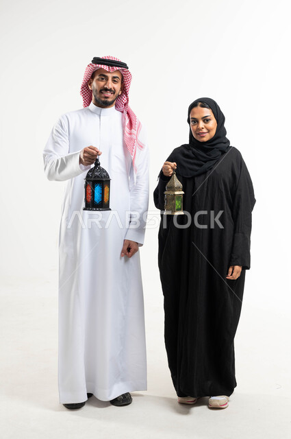بورتريه لزوجان عربيان خليجيان سعوديان ، فانوس رمضان ، الإستعداد لقدوم شهر رمضان المبارك ، المناسبات الدينية والأعياد الإسلامية ، رمضان كريم ، إسلاميات وعبادة ، خلفية بيضاء ، صورة بالطول الكامل