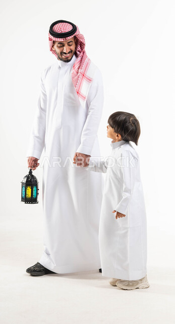 بورتريه لرجل عربي خليجي سعودي مع إبنه ، فانوس رمضان ، الإستعداد لقدوم شهر رمضان المبارك ، المناسبات الدينية والأعياد الإسلامية ، رمضان كريم ، إسلاميات وعبادة ، خلفية بيضاء ، صورة بالطول الكامل