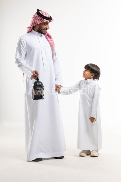 بورتريه لرجل عربي خليجي سعودي مع إبنه ، فانوس رمضان ، الإستعداد لقدوم شهر رمضان المبارك ، المناسبات الدينية والأعياد الإسلامية ، رمضان كريم ، إسلاميات وعبادة ، خلفية بيضاء ، صورة بالطول الكامل