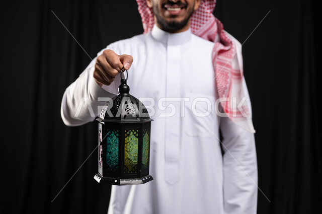 صورة مقربة لرجل عربي خليجي سعودي ، فانوس رمضان ، الإستعداد لقدوم شهر رمضان المبارك ، المناسبات الدينية والأعياد الإسلامية ، رمضان كريم ، إسلاميات وعبادة ، خلفية سوداء