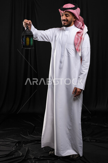 بورتريه لرجل عربي خليجي سعودي ، فانوس رمضان ، الإستعداد لقدوم شهر رمضان المبارك ، المناسبات الدينية والأعياد الإسلامية ، رمضان كريم ، إسلاميات وعبادة ، خلفية سوداء ، صورة بالطول الكامل