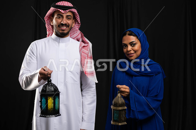 بورتريه لزوجان عربيان خليجيان سعوديان ، فانوس رمضان ، الإستعداد لقدوم شهر رمضان المبارك ، المناسبات الدينية والأعياد الإسلامية ، رمضان كريم ، إسلاميات وعبادة ، خلفية سوداء