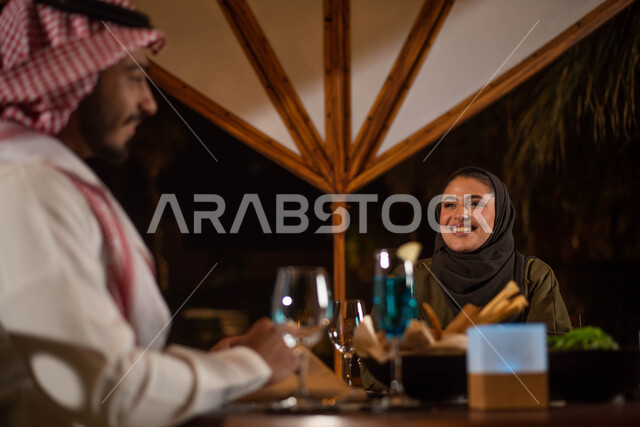 زوجان عربيان خليجيان سعوديان يستمتعان بتبادل الحديث  في احد المقاهي السعودية، تناول المشروبات الباردة، نقاشات وحوارات، قضاء أوقات ممتعة، أجواء عائلية سعيدة، مقهى سعودي