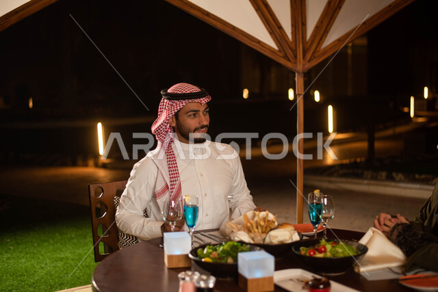 زوجان عربيان خليجيان سعوديان يستمتعان بتبادل الحديث  في احد المقاهي السعودية، تناول المشروبات الباردة، نقاشات وحوارات، قضاء أوقات ممتعة، أجواء عائلية سعيدة، مقهى سعودي