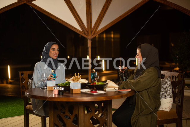 صديقتان عربيتان خليجيتان سعوديتان تستمتعان بتبادل الحديث في احد المقاهي، المشروبات الباردة، ايماءات وجه سعيدة، حوارات ونقاشات، قضاء أوقات ممتعة، أجواء سعيدة، مقهى سعودي