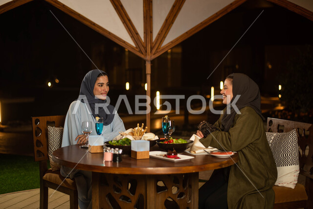 صديقتان عربيتان خليجيتان سعوديتان تستمتعان بتبادل الحديث في احد المقاهي، المشروبات الباردة، ايماءات وجه سعيدة، حوارات ونقاشات، قضاء أوقات ممتعة، أجواء سعيدة، مقهى سعودي