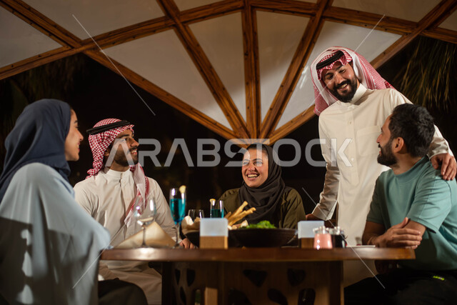 Saudi Gulf Arab friends enjoying an exchange of conversation in a Saudi cafe, cold drinks, a Saudi diwaniya, discussions and dialogues, spending enjoyable times, people and acquaintance, a happy atmosphere, a Saudi cafe