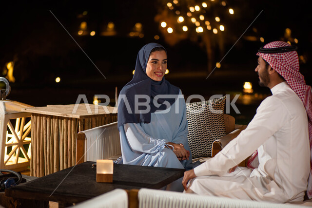 A Saudi Arabian Gulf couple enjoying an exchange of conversation in one of the recreational places, discussions and dialogues, spending pleasant times, people and acquaintance, sitting outdoors