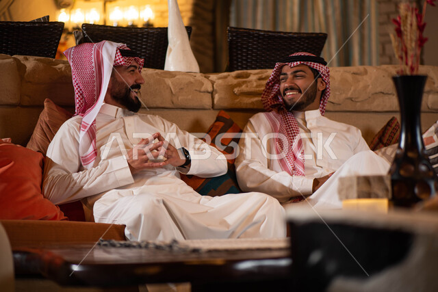 Two Saudi Arabian Gulf men dressed in Saudi dress and spending fun times, youth friendships, discussions and dialogues, happy face gestures, a youth session