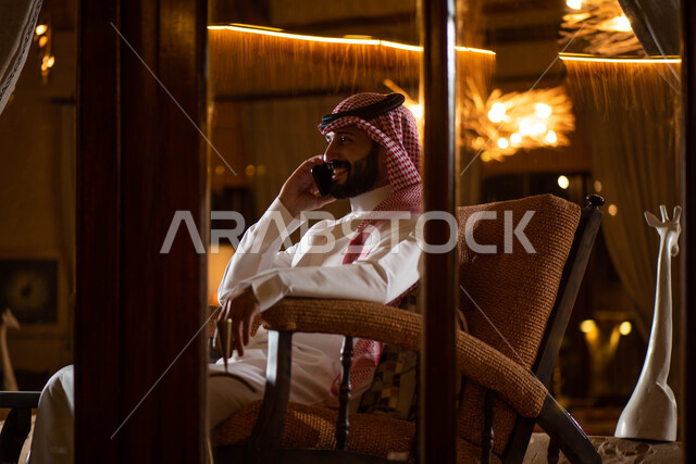 رجل عربي خليجي سعودي يقوم بإجراء مكالمة هاتفية، التواصل مع الأفراد، اتصال وتواصل، علاقات اجتماعية، دردشة وتعارف، التواصل الإجتماعي، جلسة سعودية