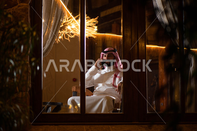 رجل عربي خليجي سعودي يقوم بإجراء مكالمة هاتفية، التواصل مع الأفراد، اتصال وتواصل، علاقات اجتماعية، دردشة وتعارف، التواصل الإجتماعي، جلسة سعودية