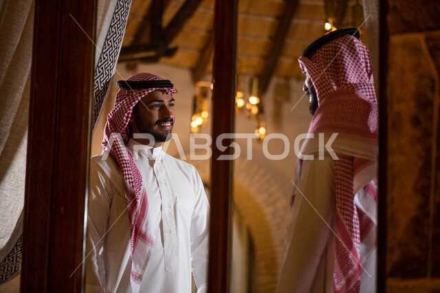 رجلان عربيان خليجيان سعوديان يرتديان الزي السعودي ويقفان امام النافذة، صداقات شباب، نقاشات وحوارات