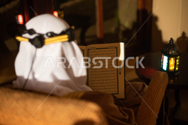 رجل عربي خليجي سعودي يرتدي زي تراثي سعودي للمناسبات الوطنية ويقراء القرآن الكريم، المناسبات الدينية والأعياد الإسلامية، فانوس رمضان، إستقبال شهر رمضان، أجواء رمضانية، يوم التأسيس السعودي