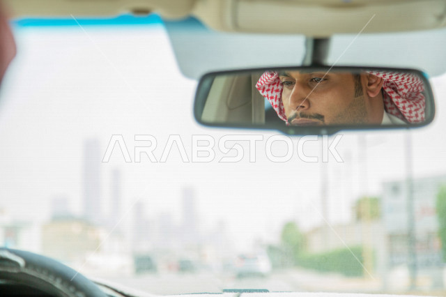 انعكاس على المرآة لصورة سائق عربي خليجي سعودي يقود سيارة الاجرة  ،خدمة توصيل الركاب ، خدمات النقل الامنة ، دروس القيادة ، التاكسي الاخضر في السعودية