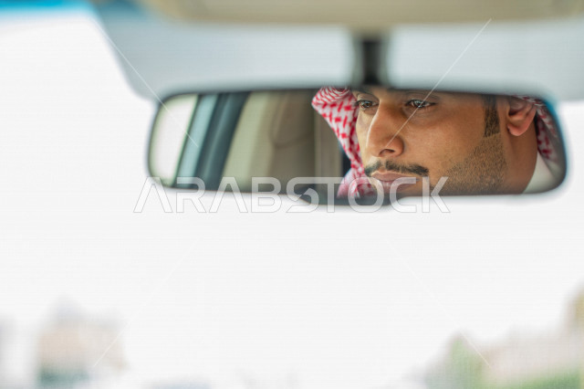 انعكاس على المرآة لصورة سائق عربي خليجي سعودي يقود سيارة الاجرة  ،خدمة توصيل الركاب ، خدمات النقل الامنة ، دروس القيادة ، التاكسي الاخضر في السعودية