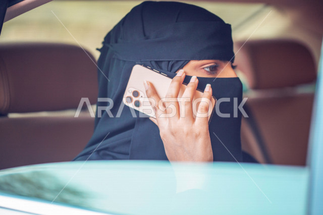 سيدة عربية خليجية سعودية داخل السيارة ،تقوم باجراء مكالمة عبر الهاتف المحمول ،مستاجرة سيارة تاكسي تستخدم تطبيق خدمة توصيل الركاب ، طلبات الاونلاين ،  التاكسي الاخضر في السعودية