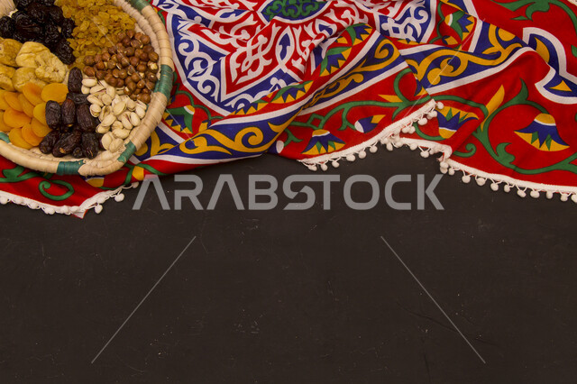 فواكهة مجففة داخل سلة صغيرة من الخوص على خلفية خشبية سوداء ، زينة رمضان ، رمضان كريم