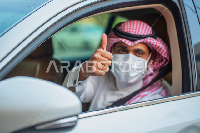رجل عربي خليجي سعودي داخل السيارة يرتدي الكمامة للوقاية من فايروس كورونا و يرفع اصبع الابهام لاعلى،  سائق معجب بخدمات التاكسي الاخضر  ، خدمة توصيل الركاب الامنة ، التاكسي الاخضر في السعودية