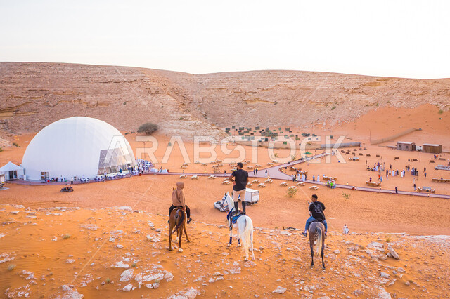مجموعة من الشباب العرب الخليجيين السعوديين يمتطون الحصان العربي الاصيل، خيمة قبة الدائرية نصف الشفافة في مخيم نوكس بصحراء المملكة العربية السعودية، الجبال والمرتفعات، الكثبان الرملية، الطبيعة الصحراوية