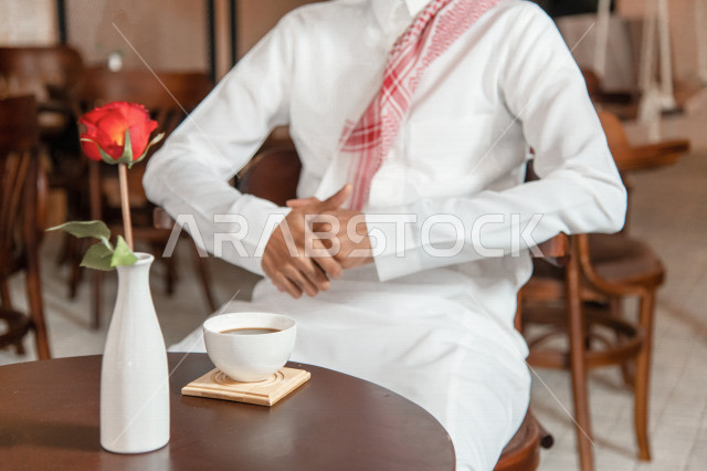 رجل عربي سعودي خليجي يجلس في مقهى, طلب القهوه من متجر القهوه السعودي, الإستمتاع بشرب القهوه في أجواء هادئه, قضاء وقت ممتع خارج المنزل, تسليه وترفيه، مقاهي في المملكه العربيه السعوديه