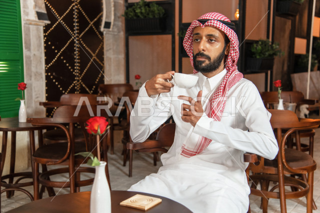 رجل عربي سعودي خليجي يجلس في مقهى, طلب القهوه من متجر القهوه السعودي, الإستمتاع بشرب القهوه في أجواء هادئه, قضاء وقت ممتع خارج المنزل, تسليه وترفيه، مقاهي في المملكه العربيه السعوديه