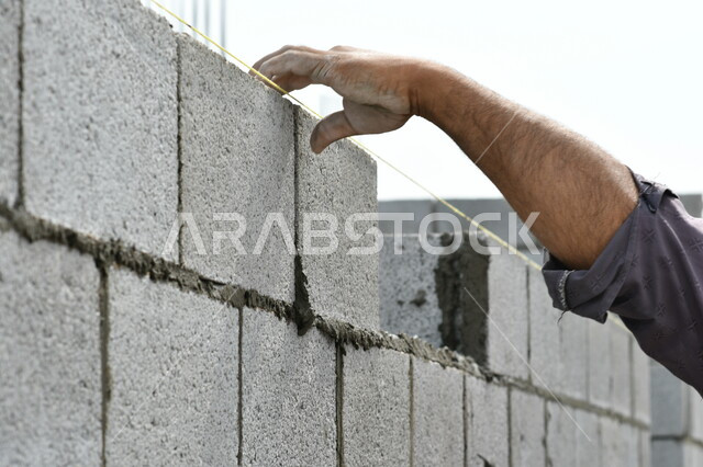 صورة مقربة لعامل بناء يقوم ببناء جدار من الطوب والاسمنت، قالب طوبي، اعمال البناء، حائط حجري، ادوات ومعدات البناء