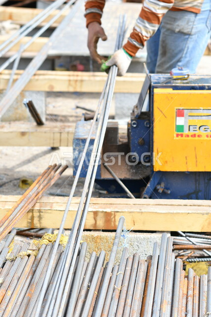 صورة مقربة لعامل بناء يقوم بتجهيز اسياخ البناء المعدنية، معدات وادوات البناء، اعمال البناء، اسياخ معدنية، الحديد الصلب