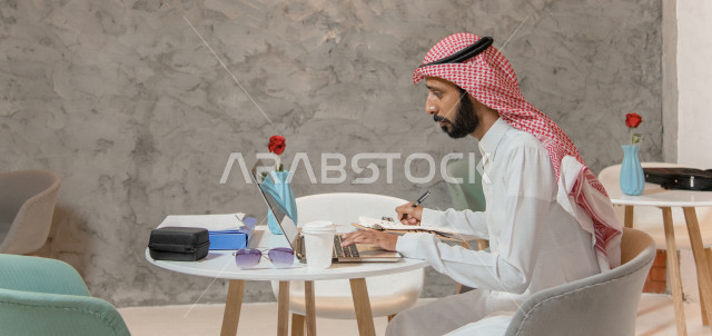 رجل أعمال عربي سعودي خليجي في المقهى, إجتماع عمل عن بعد, انجهاز مهام العمل عبر جهاز الحاسوب, إدارة الأعمال خارج الشركه,  الإستمتاع بشرب القهوه في متجر القهوه, مقاهي في المملكه العربيه السعوديه