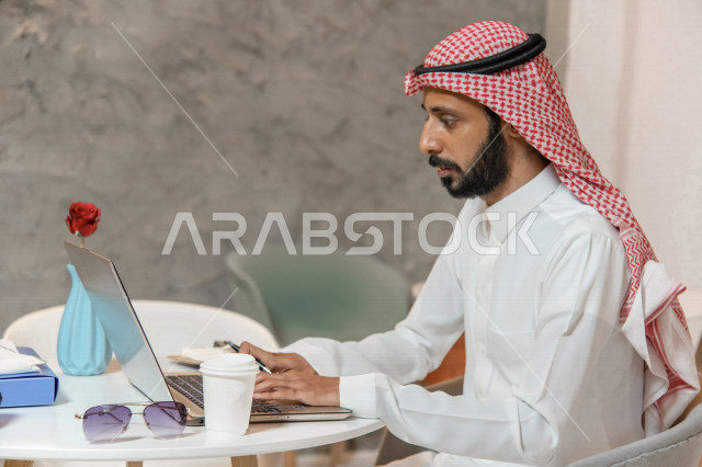 رجل أعمال عربي سعودي خليجي في المقهى, إجتماع عمل عن بعد, انجهاز مهام العمل عبر جهاز الحاسوب, إدارة الأعمال خارج الشركه,  الإستمتاع بشرب القهوه في متجر القهوه, مقاهي في المملكه العربيه السعوديه