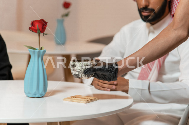 A Saudi Arabian Gulf man sitting in a café, ordering coffee from the Saudi coffee shop, enjoying drinking coffee in a calm atmosphere, spending quality time outside the house, entertainment and entertainment, cafés in the Kingdom of Saudi Arabia