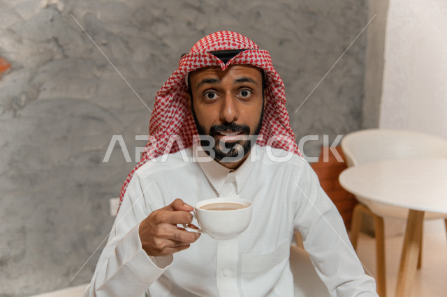 رجل عربي سعودي خليجي يجلس في مقهى, طلب القهوه من متجر القهوه السعودي, الإستمتاع بشرب القهوه في أجواء هادئه, قضاء وقت ممتع خارج المنزل, تسليه وترفيه، مقاهي في المملكه العربيه السعوديه