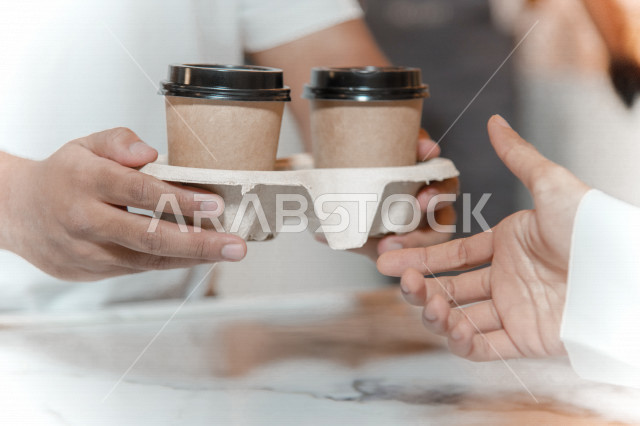 رجل عربي سعودي خليجي يستلم الطلب من المقهى, الطلب من متجر القهوه, تسليم القهوه للزبائن, الإستمتاع بشرب القهوه في المقهى, الدفع عند الكاشير, مقاهي في المملكه العربيه السعوديه