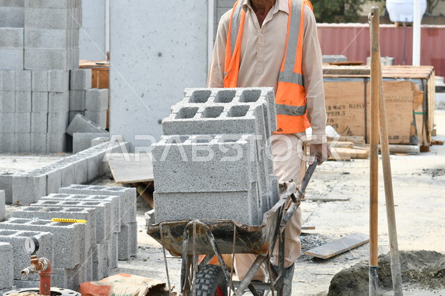 A construction worker pulls a cart transporting building materials filled with bricks , Bricks, construction works, building stones, building walls and ceilings, construction tools and equipment